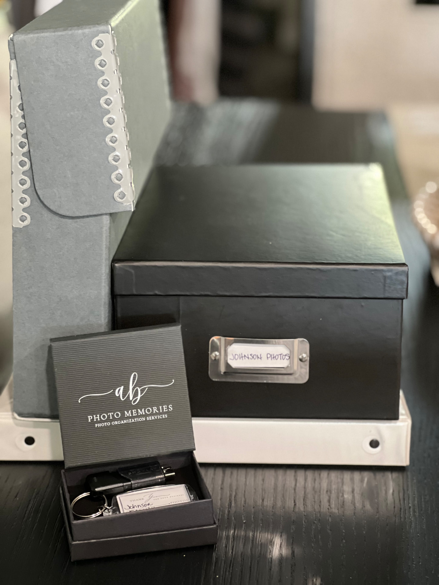 Labeled archival photo box, family album and a USB drive in a gift box after professional photo organizing