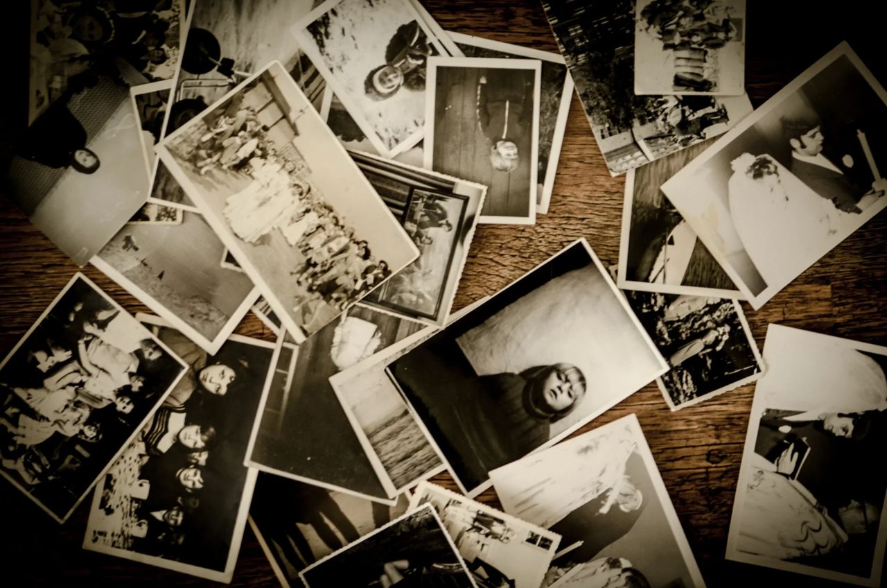 A tabletop overflowing with vintage family photographs and overflowing shoeboxes